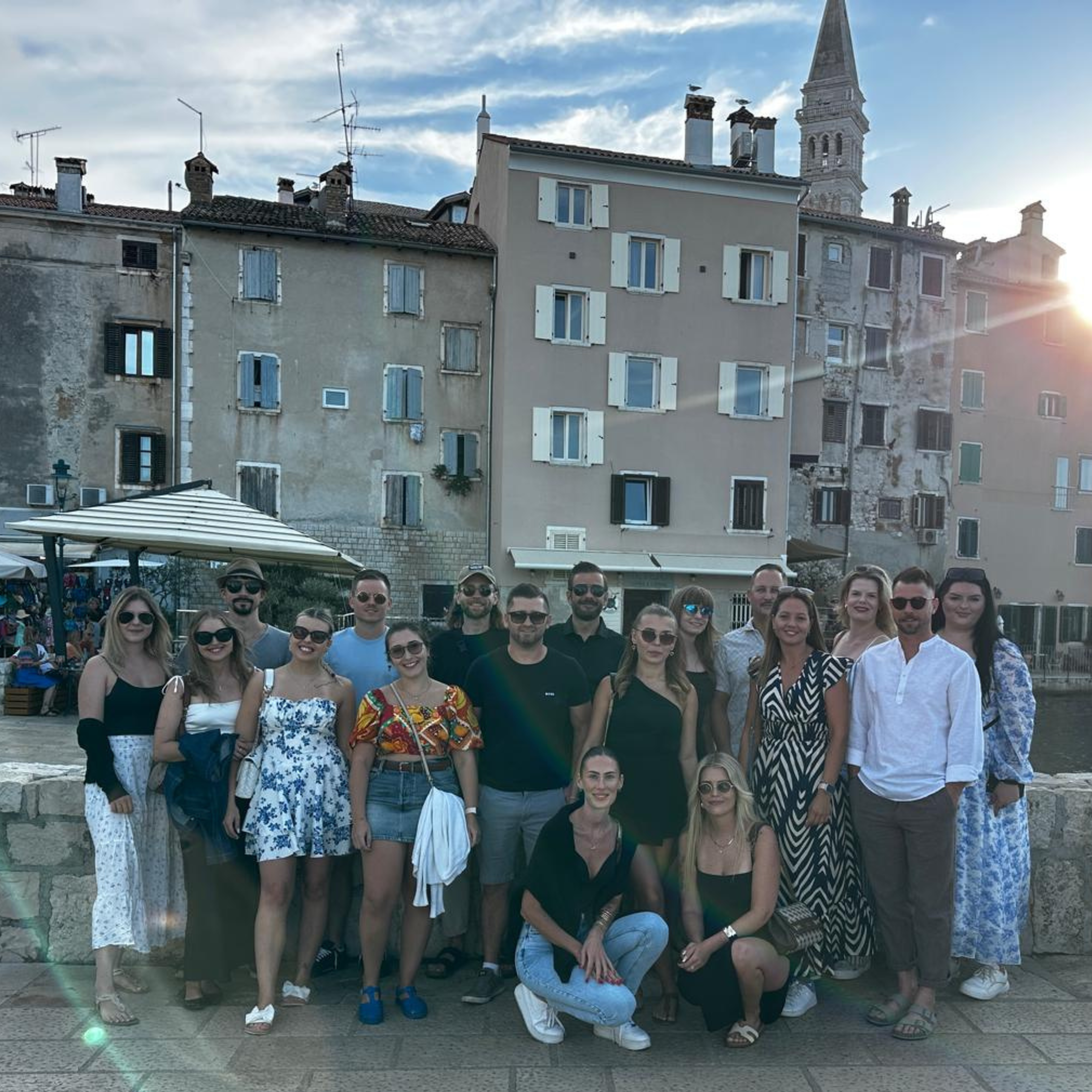 Das Team versammelte sich bei Sonnenuntergang vor farbenfrohen Gebäuden im mediterranen Stil.